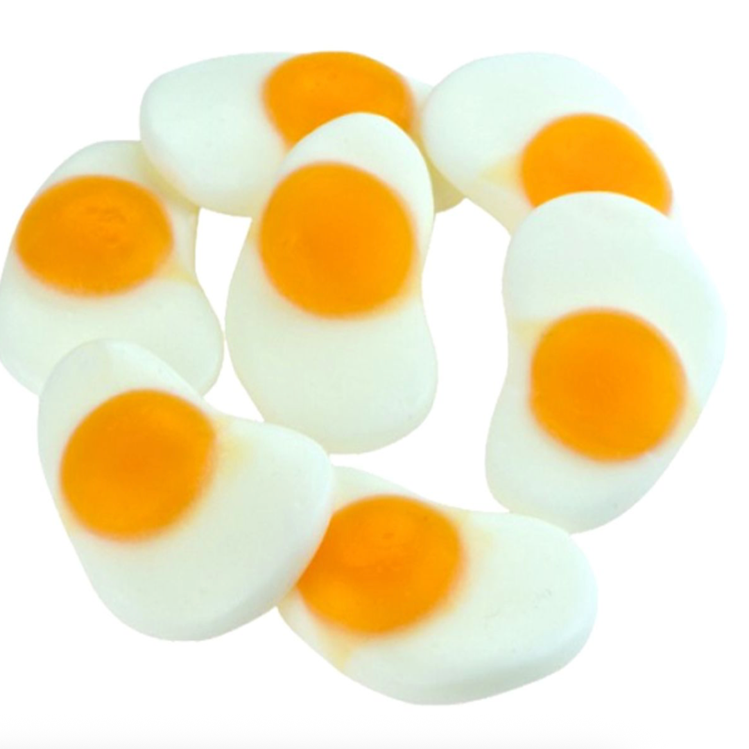 Gummy candies shaped like boiled eggs with orange centers on a white background