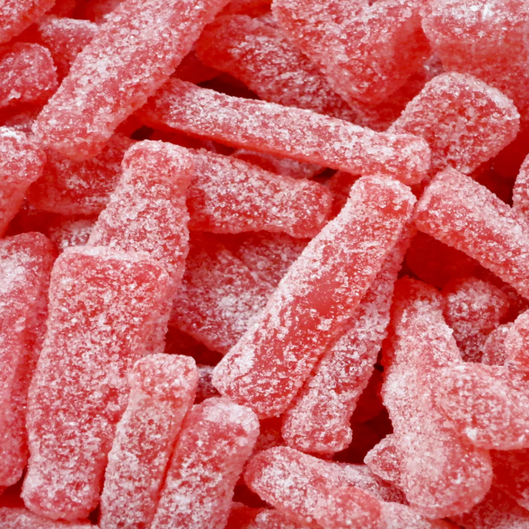 Close-up of many pink candies with a sugary coating shaped as bottles.