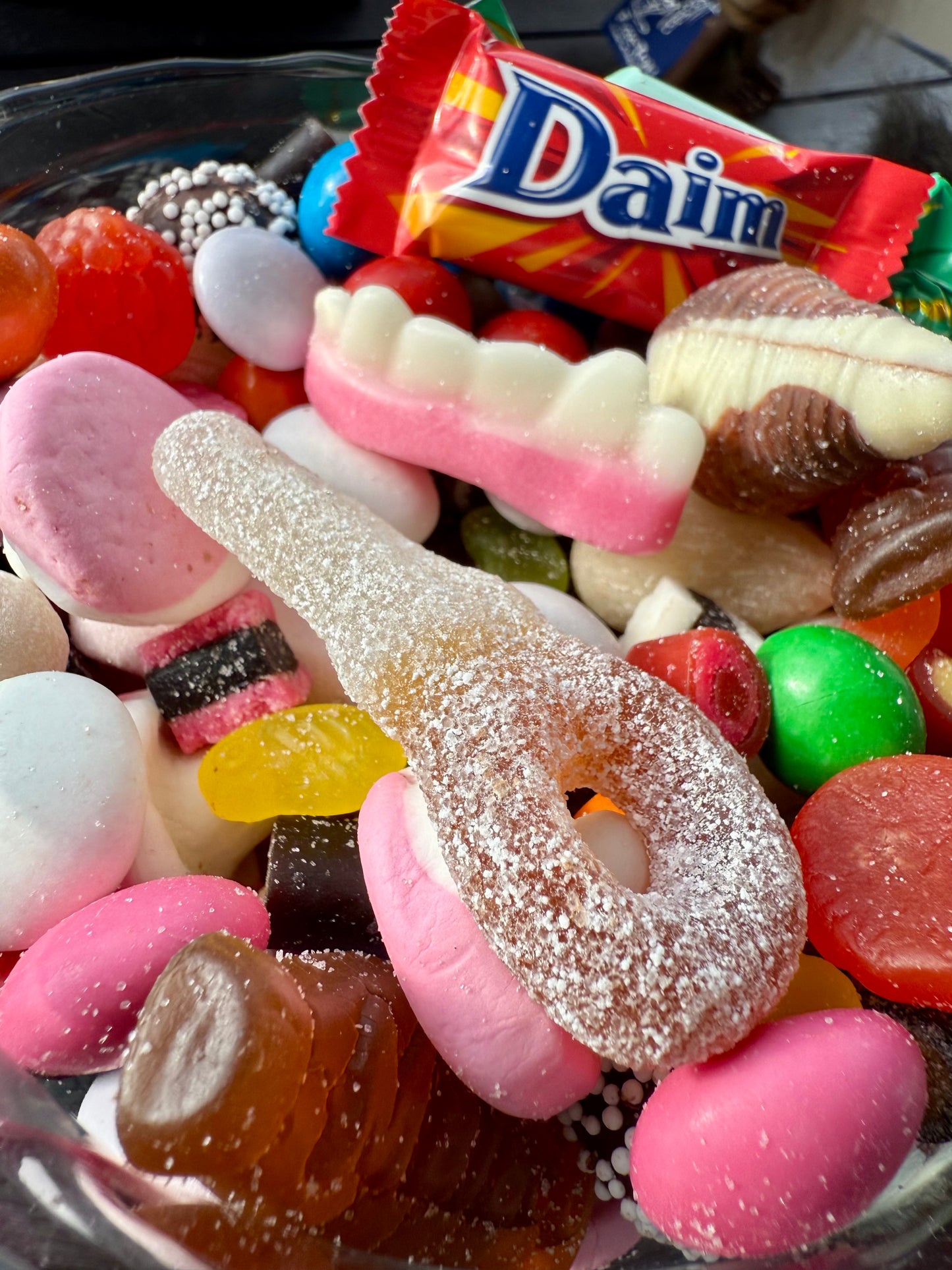 Assorted colorful candies with a Daim bar in the background