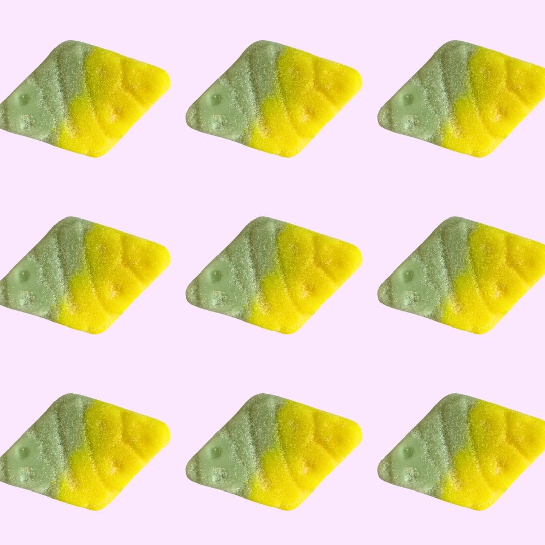 Green and yellow triangular candies on a pink background