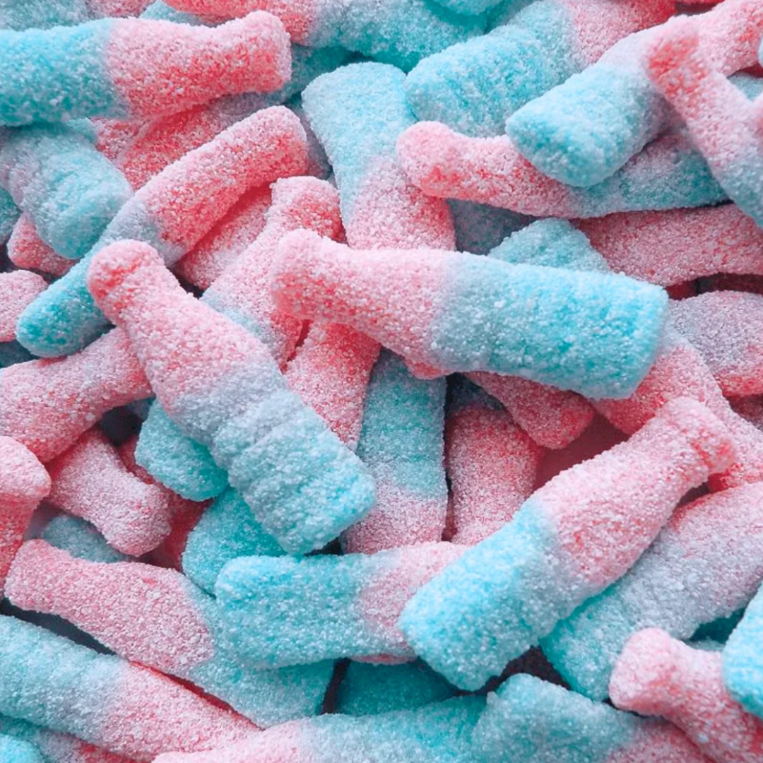 Close-up of pink and blue gummies shape as bottles. Coated in Sour sugar
