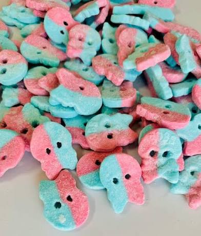 Colorful pink and blue skull-shaped candies on a white surface