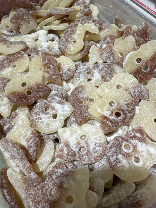 Close-up of skull-shaped candy with brown and beige colors covered in sour sugar. Marked Bubs
