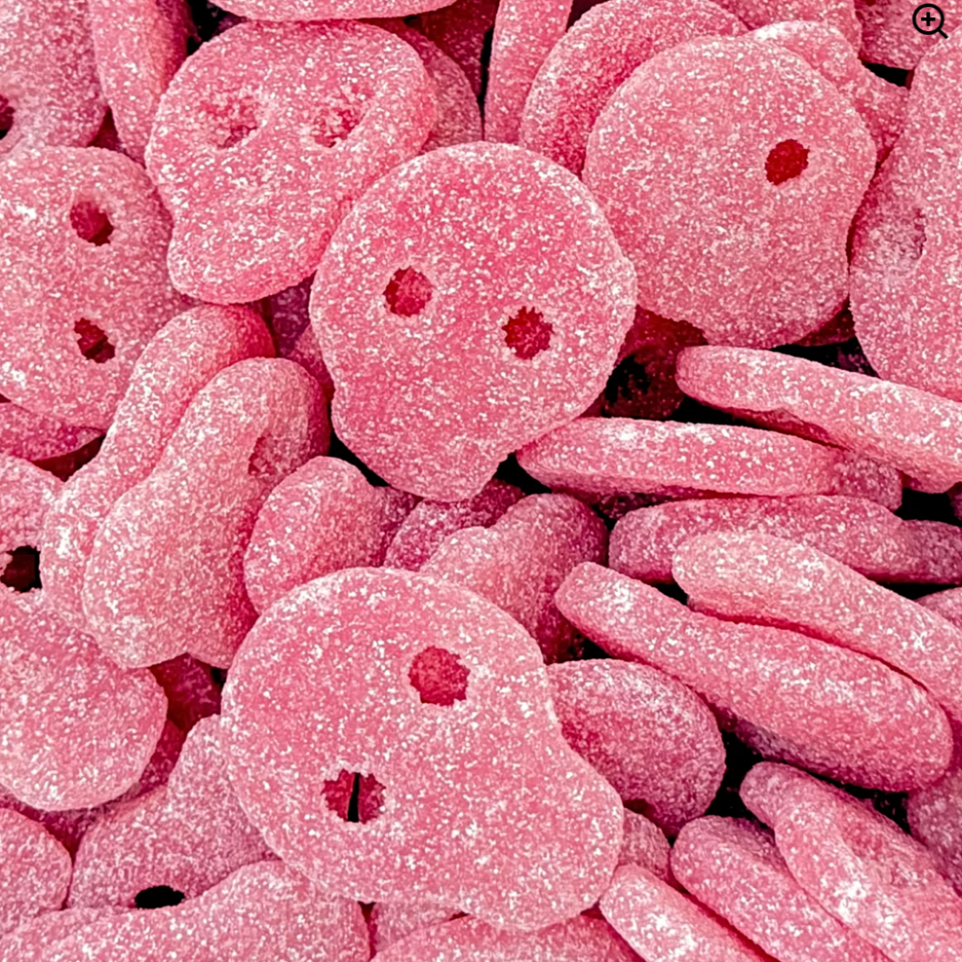 Close-up of pink skull-shaped gummy candies with red centers.