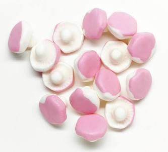 Pink and white candy pieces shaped as mushrooms on a white background